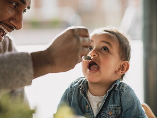 Un papá y su hijo comiendo alimentos pare evitar alergias en bebés.
