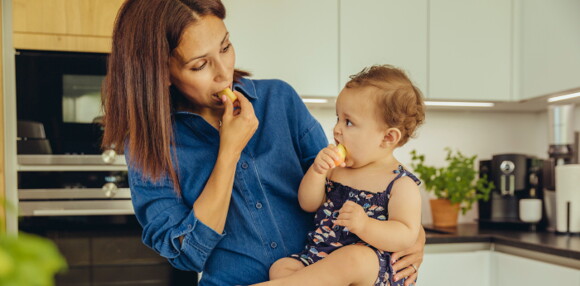 Mamá con su hija comiendo alimentos para evitar los tipos de alergias en bebés